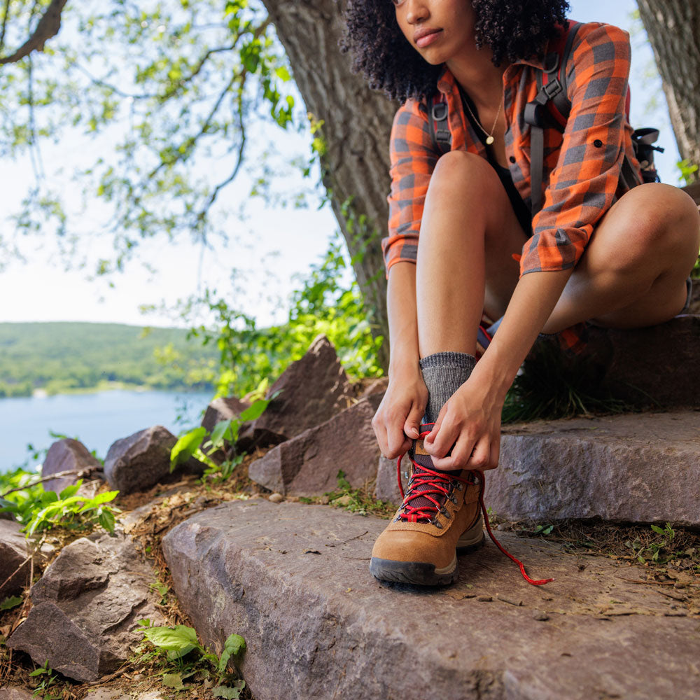 Femme s'arrêtant de faire de la randonnée dans les bois, chaussant ses bottes de randonnée #1-choisir-son-profil_low