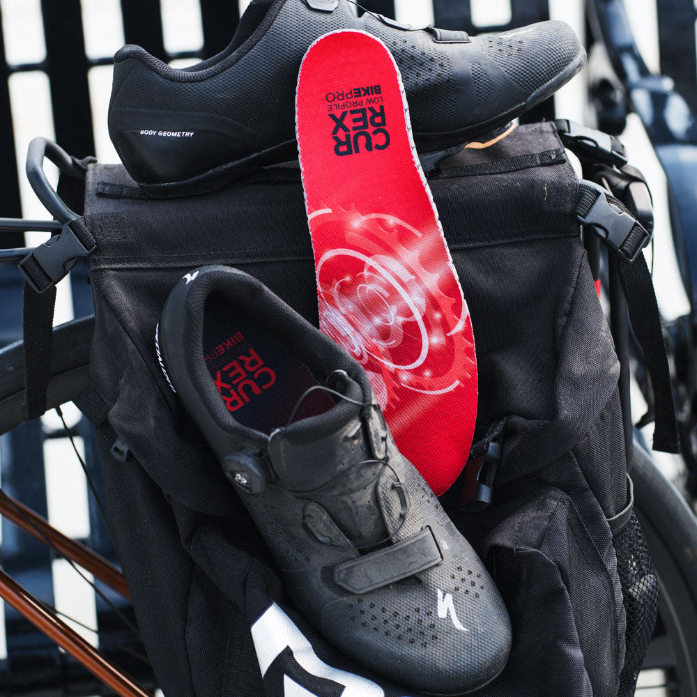 Chaussures de cyclisme noires assises contre le sac à dos avec semelles CURREX BIKEPRO rouges à profil bas #1-choix-de-votre-profil_low